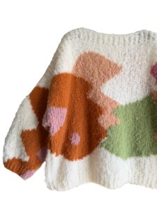 In de sweater zijn organische vormen ingebreid met intarsia techniek. De Kyle sweater is gemaakt in offwhite met beige, oranje, roze en groen.